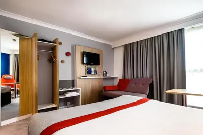 a hotel room with a bed and a couch at Holiday Inn Express London Stansted Airport by IHG in Stansted Mountfitchet