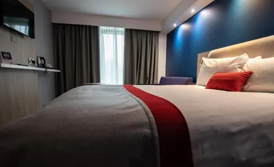 a hotel room with a large bed with a red pillow at Holiday Inn Express London Stansted Airport by IHG in Stansted Mountfitchet
