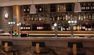 a bar with a lot of bottles of wine at Holiday Inn Express London Stansted Airport by IHG in Stansted Mountfitchet