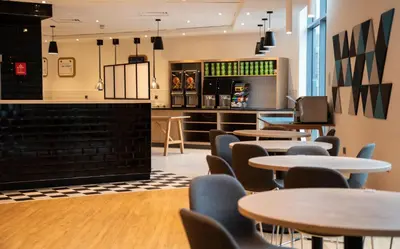 a restaurant with tables and chairs and a counter at Holiday Inn Express London Stansted Airport by IHG in Stansted Mountfitchet
