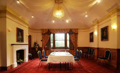 a dining room with a table and chairs and a chandelier at Marygreen Manor in Brentwood