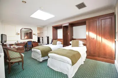 a hotel room with two beds and a desk at Marygreen Manor in Brentwood