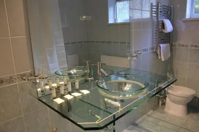 a bathroom with a glass counter with two sinks and a toilet at Desalis Hotel London Stansted in Elsenham