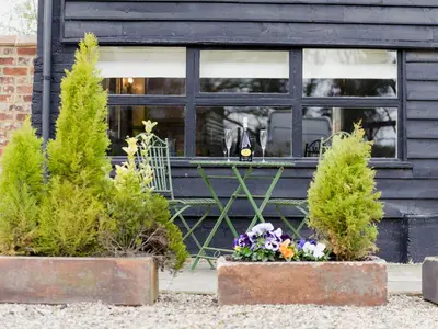 a table and chairs in front of a building with plants at The Dairy - Ukc1546 in Heveningham