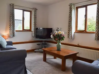 a living room with a vase of flowers on a coffee table at Millers Rest in Willingham