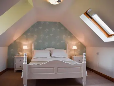a bedroom with a white bed in a attic at Millers Rest in Willingham