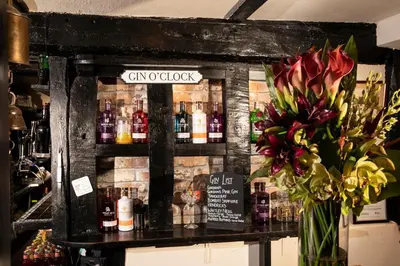 a bar with a vase of flowers on a counter at The Cock Inn Hotel in Sheering