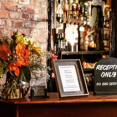 a table with a vase of flowers and a sign at The Cock Inn Hotel in Sheering