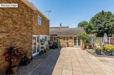 a brick house with a courtyard with potted plants at Little Croft in Haddenham