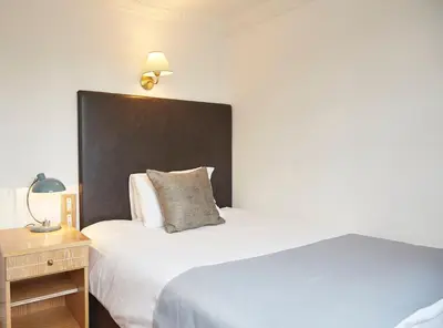 a hotel room with two beds and a lamp and a table at White Hart Hotel by Greene King Inns in Coggeshall