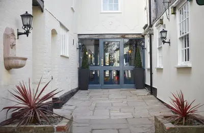 an alley with a blue door on a building at White Hart Hotel by Greene King Inns in Coggeshall