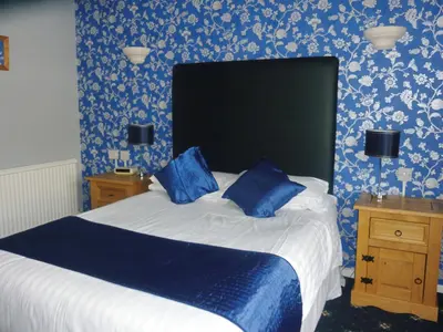 a bedroom with a bed with blue and white wallpaper at The Oakland Hotel in Woodham Ferrers