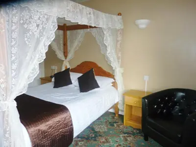 a bedroom with a canopy bed and a chair at The Oakland Hotel in Woodham Ferrers
