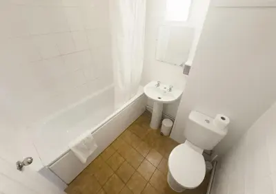 a white bathroom with a toilet and a sink at The Oakland Hotel in Woodham Ferrers