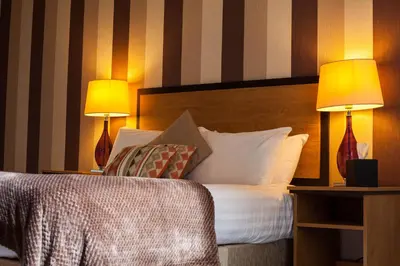 a hotel room with a bed with two lamps at The Riverside House Hotel in Mildenhall