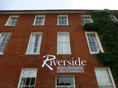 a red brick building with a sign on it at The Riverside House Hotel in Mildenhall