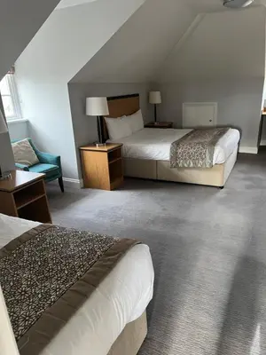 a hotel room with two beds and a chair at The Riverside House Hotel in Mildenhall