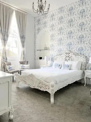 a bedroom with a bed with blue and white wallpaper at The Riverside House Hotel in Mildenhall
