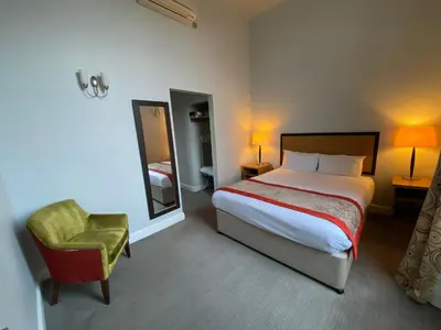 a bedroom with a bed and a chair and a mirror at The Riverside House Hotel in Mildenhall