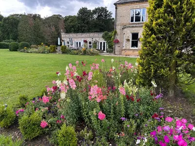 a garden with pink flowers in front of a house at Broom Hall Country Hotel in Saham Toney