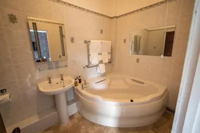 a bathroom with a large tub and a sink at Broom Hall Country Hotel in Saham Toney