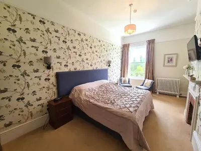 a bedroom with a bed and floral wallpaper at Broom Hall Country Hotel in Saham Toney
