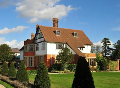 a large house with a green yard with trees at Greenwoods Hotel & Spa in Stock