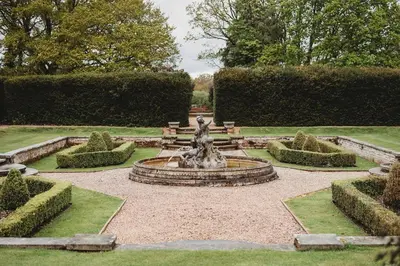 a fountain in the middle of a garden with bushes at Greenwoods Hotel & Spa in Stock
