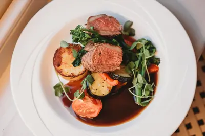 a white plate of food with meat and vegetables at Greenwoods Hotel & Spa in Stock