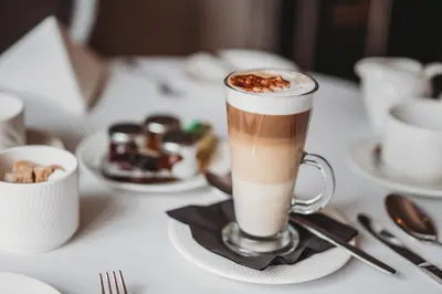 a cup of coffee sitting on a table with desserts at Greenwoods Hotel & Spa in Stock