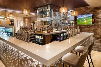 a bar in a restaurant with chairs and a tv at Holiday Inn Brentwood by IHG in Brentwood