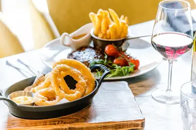 a table with a plate of food and a glass of wine at Holiday Inn Brentwood by IHG in Brentwood