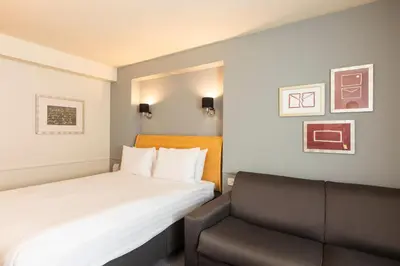 a hotel room with a bed and a chair at Holiday Inn Brentwood by IHG in Brentwood