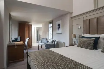 a bedroom with a large bed and a living room at Fanhams Hall, Exclusive Collection in Ware