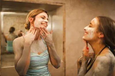 a woman brushing her face in front of a mirror at Stoke By Nayland Hotel, Golf & Spa in Leavenheath
