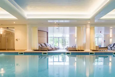 a swimming pool in a hotel with chairs at Stoke By Nayland Hotel, Golf & Spa in Leavenheath