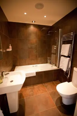 a bathroom with a tub and a sink and a toilet at Channels Hotel in Chelmsford