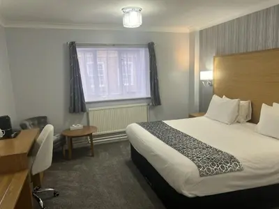 a hotel room with a bed and a desk and a window at Dolphin Hotel St Ives in St Ives