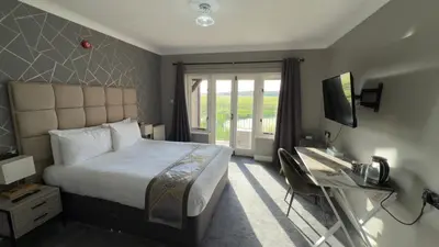 a bedroom with a bed and a desk and a television at Dolphin Hotel St Ives in St Ives