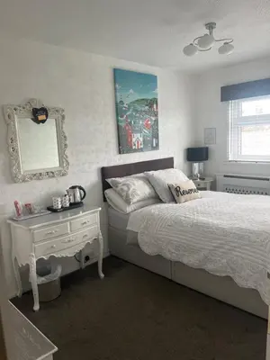 a bedroom with a bed and a table and a mirror at Southend Airport Bed & Breakfast in Rochford