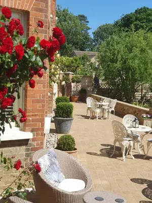 a patio with tables and chairs and red roses at Belle Vue Guest House in Denver