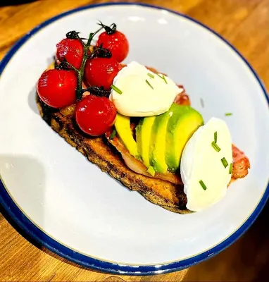 a white plate with a sandwich with tomatoes and sour cream at Belle Vue Guest House in Denver