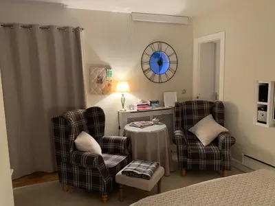 a bedroom with two chairs and a table and a clock at The Grapevine Studio in Cambridge
