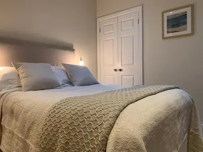 a bedroom with a large bed with white sheets and pillows at The Grapevine Studio in Cambridge