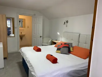 a bedroom with a large white bed with orange pillows at Woodland Lodge in Hoddesdon