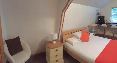 a small bedroom with a bed and a chair at Woodland Lodge in Hoddesdon