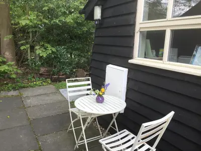 a table with two chairs and a table with a vase on it at Woodland Lodge in Hoddesdon
