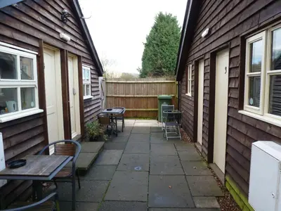 a patio with tables and chairs next to a house at Woodland Lodge in Hoddesdon