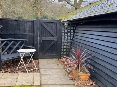 a blue house with a gate and a table and a chair at Woodland Lodge in Hoddesdon