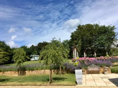 a garden with purple flowers and a fence at Snipe Vineyard Cottage in Woodbridge